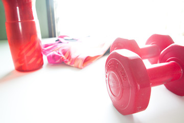 Red dumbbells, Red water bottle and sport wear in fittness backg