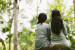 © DragonImages - Rear view of two female friends resting in park