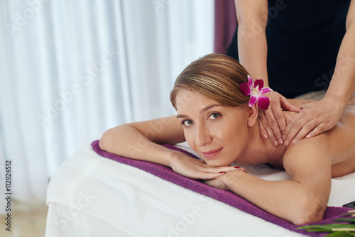 Obraz na plátně Attractive young woman looking at camera when having shoulder massage