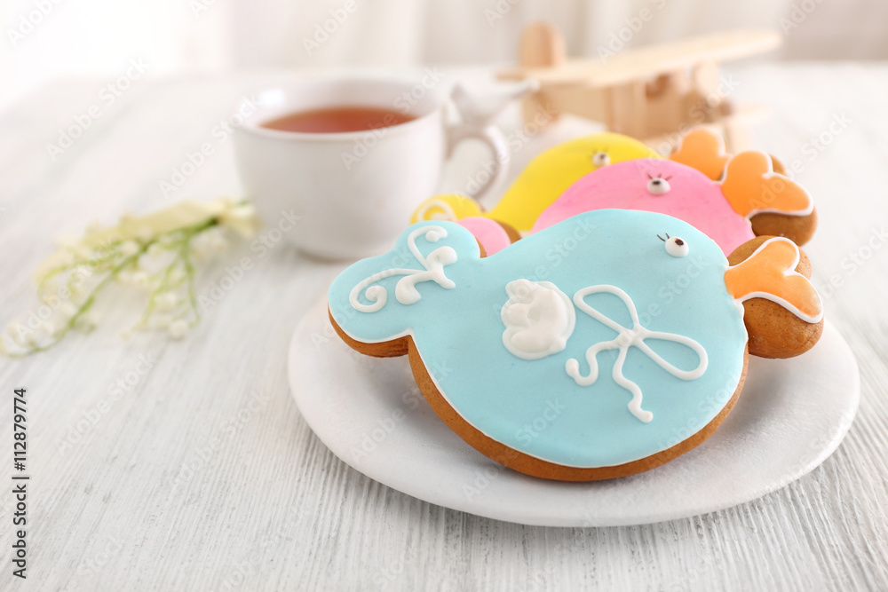 Decorative baby cookies with cup of  tea on plate