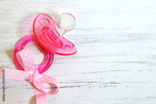 Fotografija  Baby soother with a pink ribbon