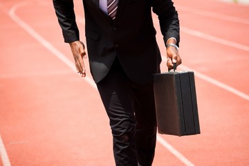 Sticker - Mid section of businessman running on a running track