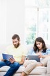 © WavebreakmediaMicro - Couple sitting on sofa and using digital tablet in living room