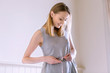 © Connect Images - Woman measuring waist with tape measure looking down smiling