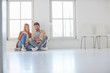 © Connect Images - Couple sitting on floor browsing digital tablet in empty new home