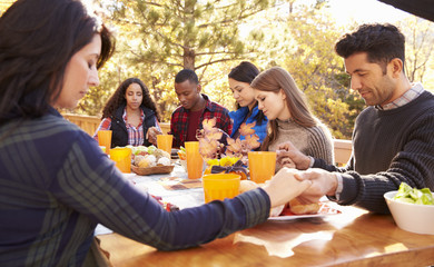 Wall Mural - Friends at a table at a barbecue saying grace before eating