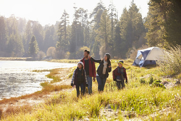 Wall Mural - Family on a camping trip walking near a lake looking away