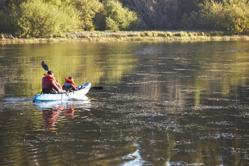 Wall Mural - Father and son kayaking on a lake, back view, distant