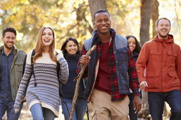 Group of six friends hiking together through a forest