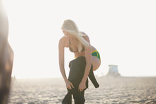 Young Woman Putting On Wetsuit On Venice Beach, California, USA