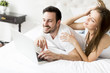 © BGStock72 - Young couple with laptop in the bed