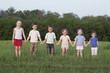 © fStop - Portrait of children holding hands in a field