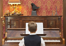 A Boy Practicing On An Upright Piano
