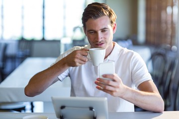 Poster - Man using mobile phone while having cup of coffee