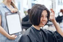 Closeup Portrait Of Hispanic Latin Girl Woman Sitting In Chair In Hair Salon Looking In Mirror At Her New Haircut, Short Bob Pixie, Happy Joy Emotion