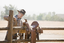 A Rancher Preparing A Horse Saddle On A Fence