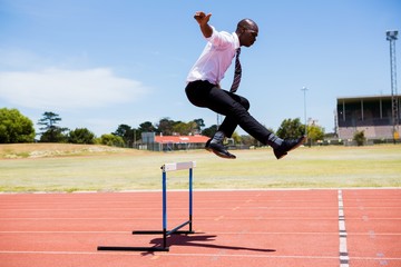 Wall Mural - Businessman jumping a hurdle while running