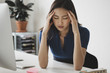 © fStop - Young businesswoman suffering from headache at desk in office