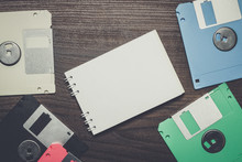 Diskettes And Blank Notebook On The Wooden Background