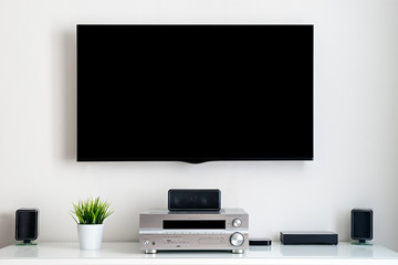 Home multimedia center - flat tv with blank black screen on wall and acoustic system in residential room interior