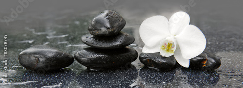 Naklejka na kafelki White orchid and black stones close up.