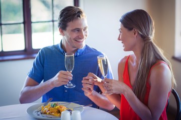 Poster - Happy young couple toasting champagne flutes while having lunch