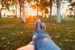 Leinwandbild Motiv Male feet in gumshoes on green grass in the park at sunset