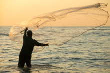 Silhouette Of The Unidentified Indian Fisherman Throwing Net In Sea On Sunset In Fort Kochi, India.