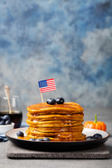 Wall Mural - Pumpkin pancakes with maple syrup and blueberries on a plate with American flag on top
