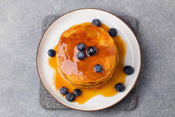 Wall Mural - Pumpkin pancakes with maple syrup and blueberries on a plate. Grey stone background Top view