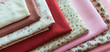stash of fabric in pastel pinks for sewing projects 

