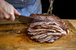 © Andrew Scrivani - Man cutting slow cooked roast beef