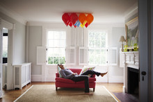Young Man Lying On Sofa And Looking At Colorful Balloons