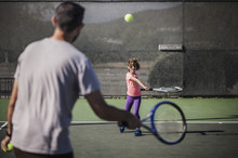 Father And Daughter Playing Tennis On Court