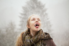 Portrait Of Young Woman Catching Snow On Tongue