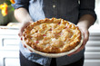 © Cavan Images - Midsection of woman holding baked rhubarb pie while standing at home