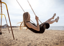 Young Woman Swinging On Swing At Beach