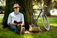 Young Man Reading Book Under Tree
