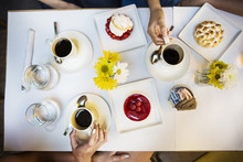 Cropped Image Of Friends Having Coffee And Dessert At Table In Restaurant