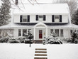 © Cavan Images - Pathway leading towards white house with snow covered plants during winter
