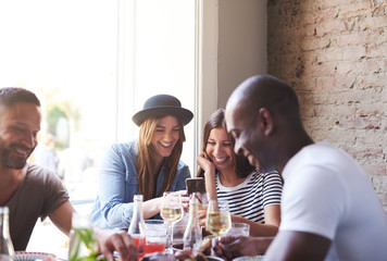 Wall Mural - Laughing women looking at phone at dinner