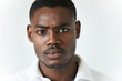 © WHstudio Leushin N - Highly-detailed close up shot of young African man with moustache and beard wearing polo shirt, looking at the camera with serious face, displeased with something. Human face expressions and emotions