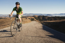 Man Riding Bicycle On Gravel Road Against Clear Sky