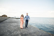 © olegparylyak - Beautiful loving couple, pride with long dress walking on pier