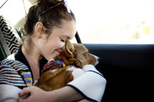 Woman Embracing Dog While Sitting In Car