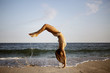 © Cavan Images - Woman doing backflip on beach