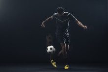 Young Athlete Playing Soccer Against Black Background
