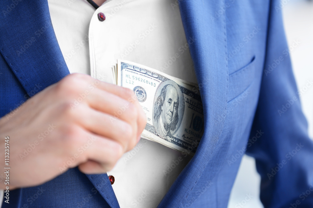 Man hiding dollar banknotes in suit