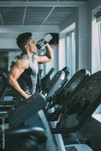 Young man in sportswear running on treadmill at gym Lerretsbilde