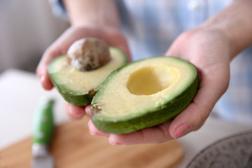 Poster - Woman holding fresh avocado in kitchen